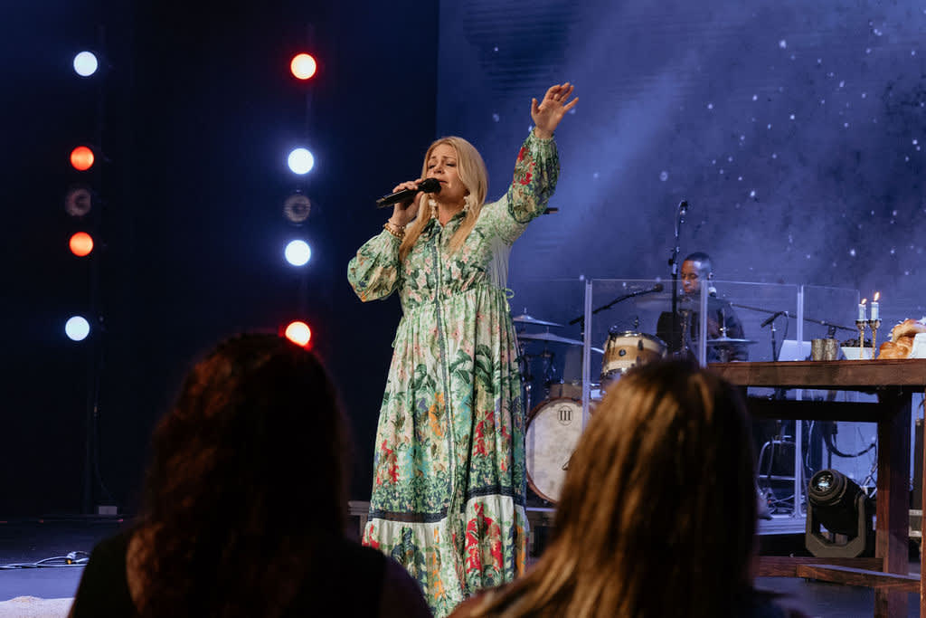 Laura Cooksey singing with arm raised