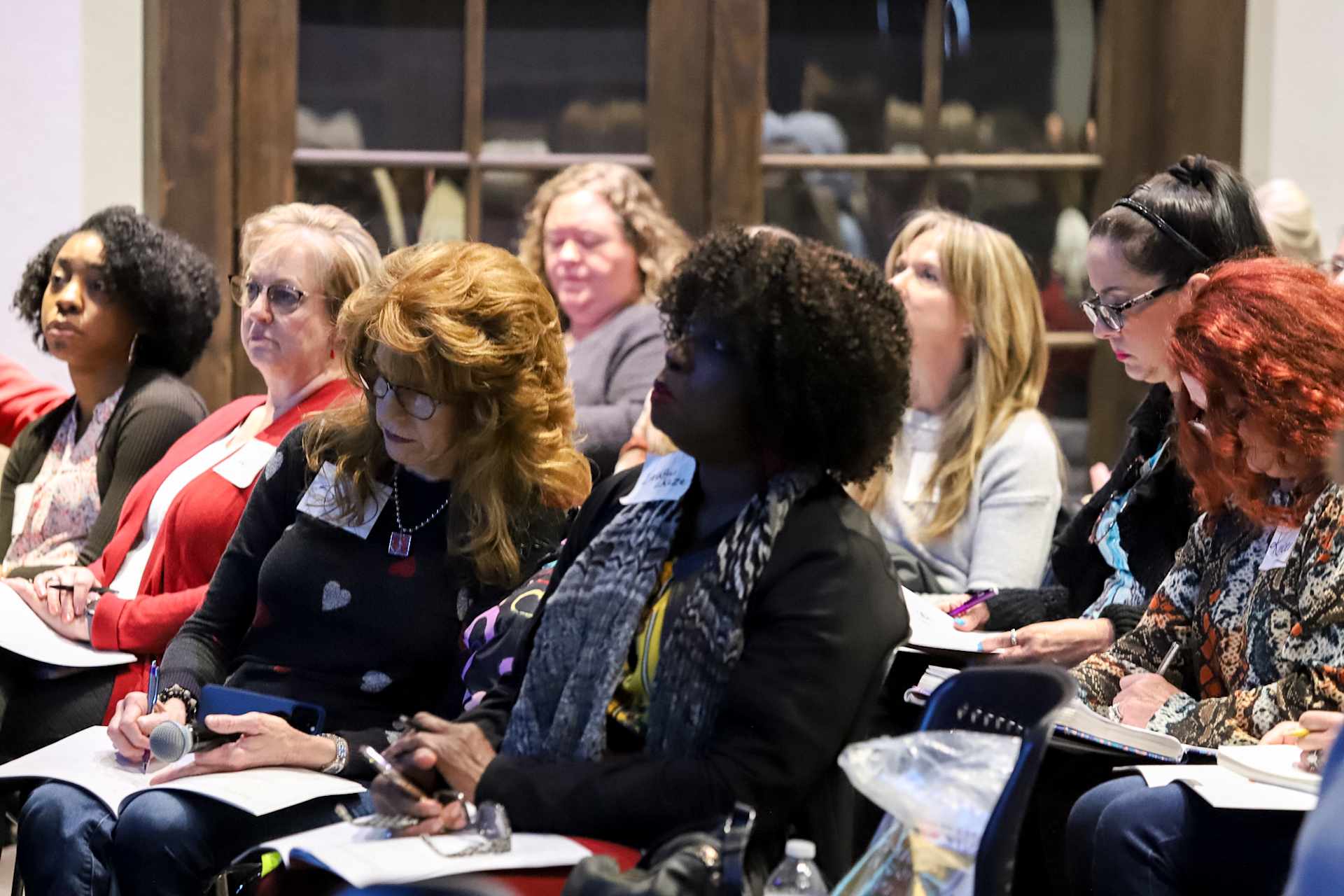 A group of women attentively listening and taking notes during a conference session