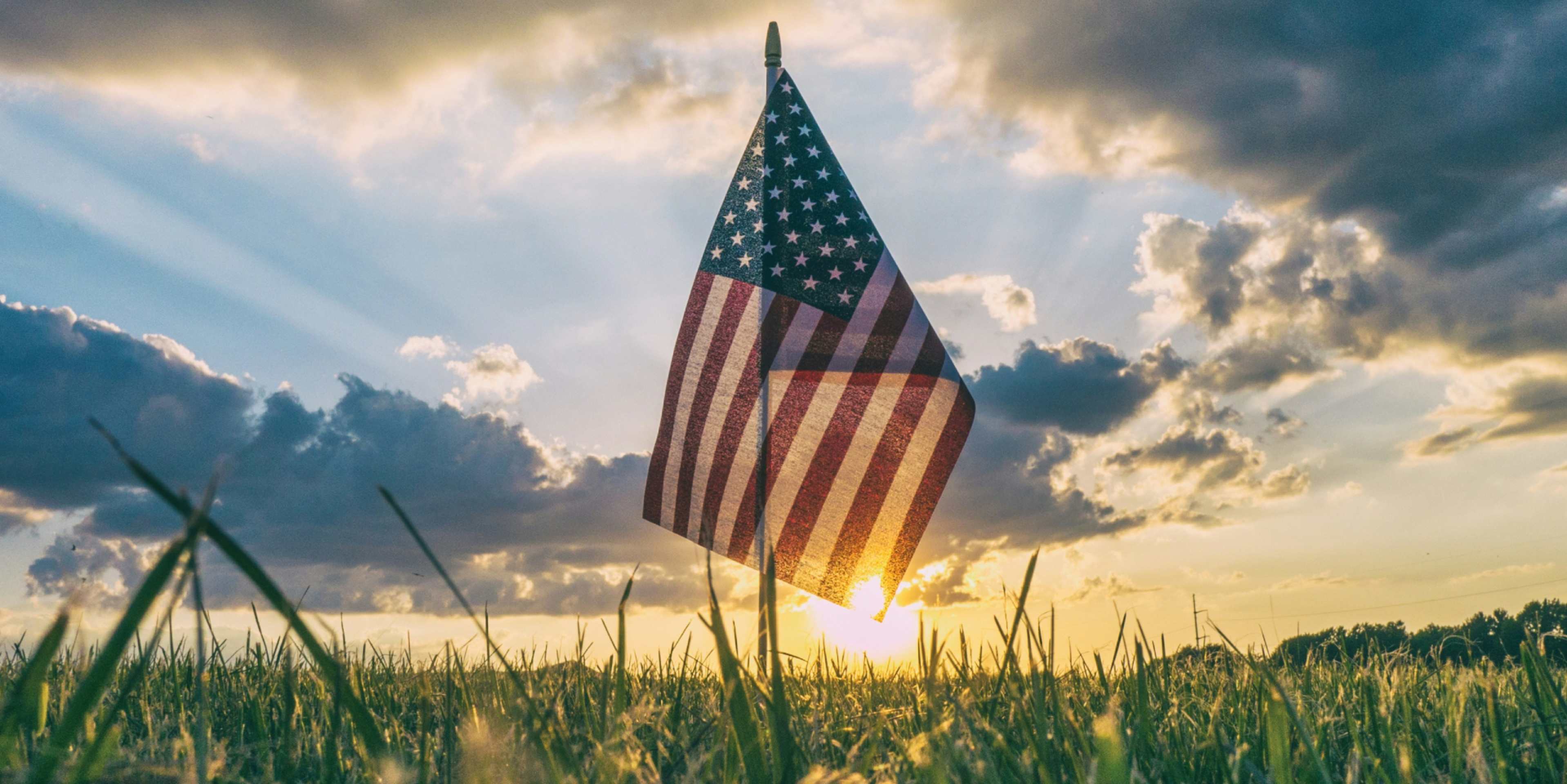 American flag in a field at sunset