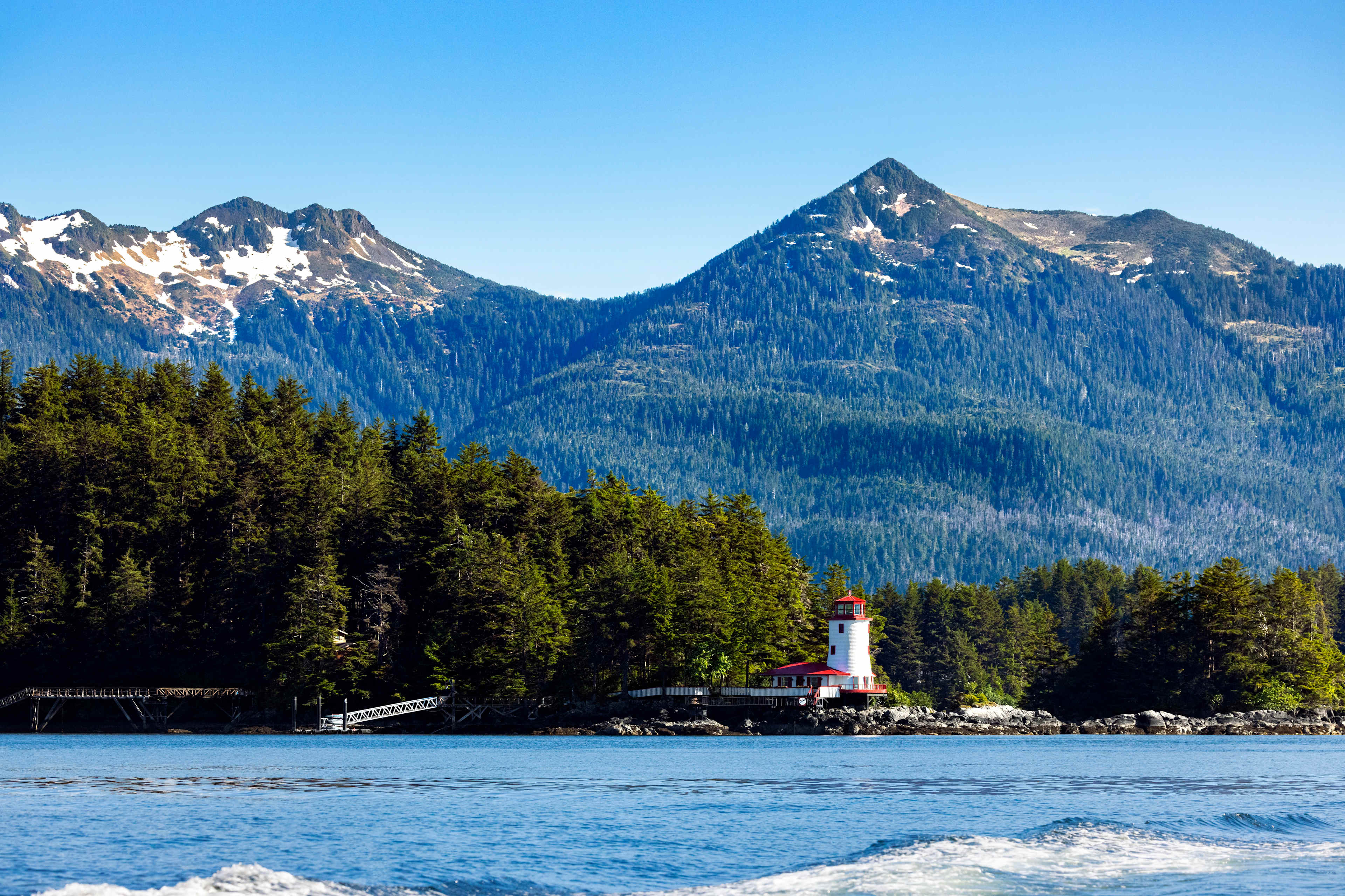 Mountain skyline along coastal waters with white lighthouse