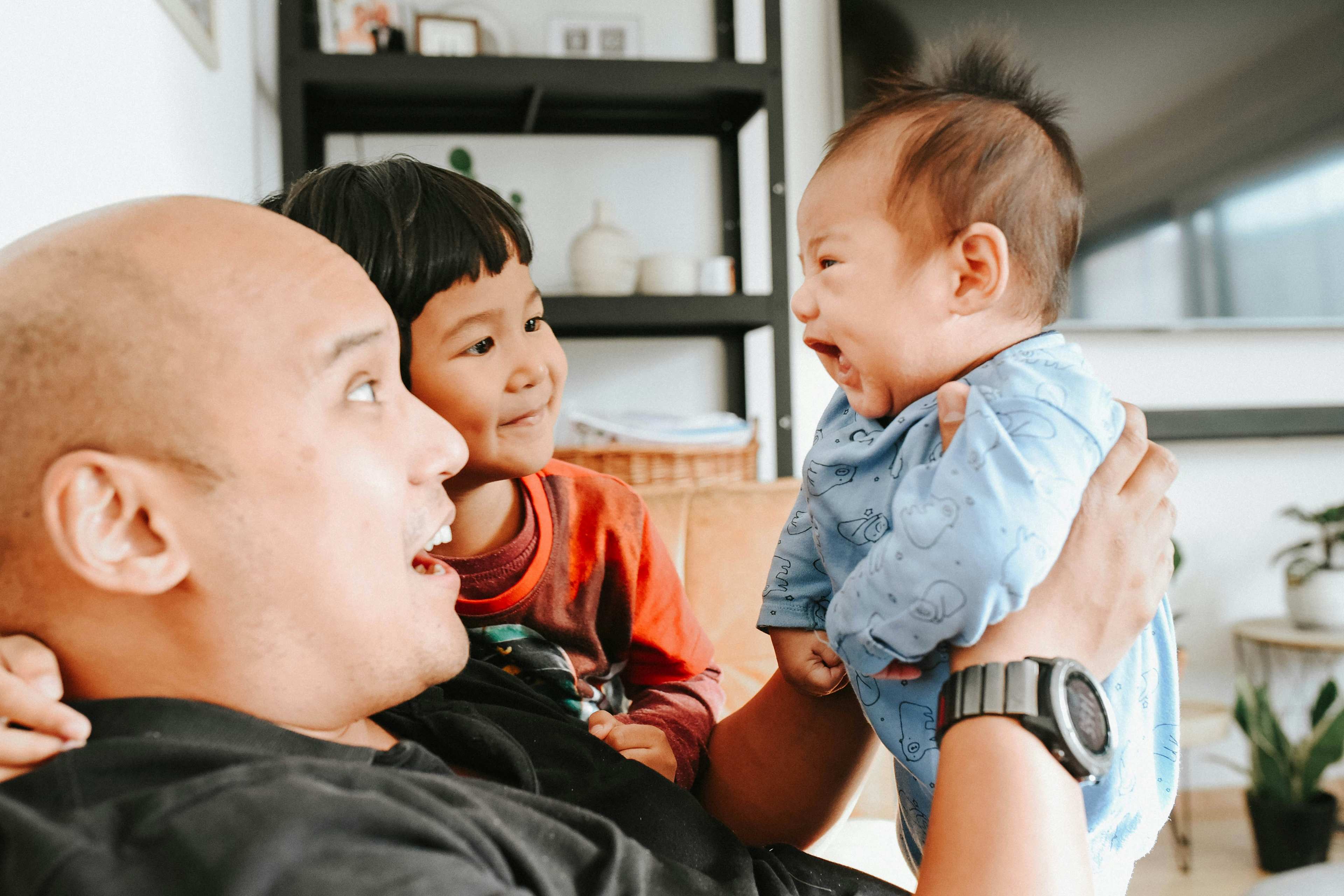 dad holding a baby with another sibling