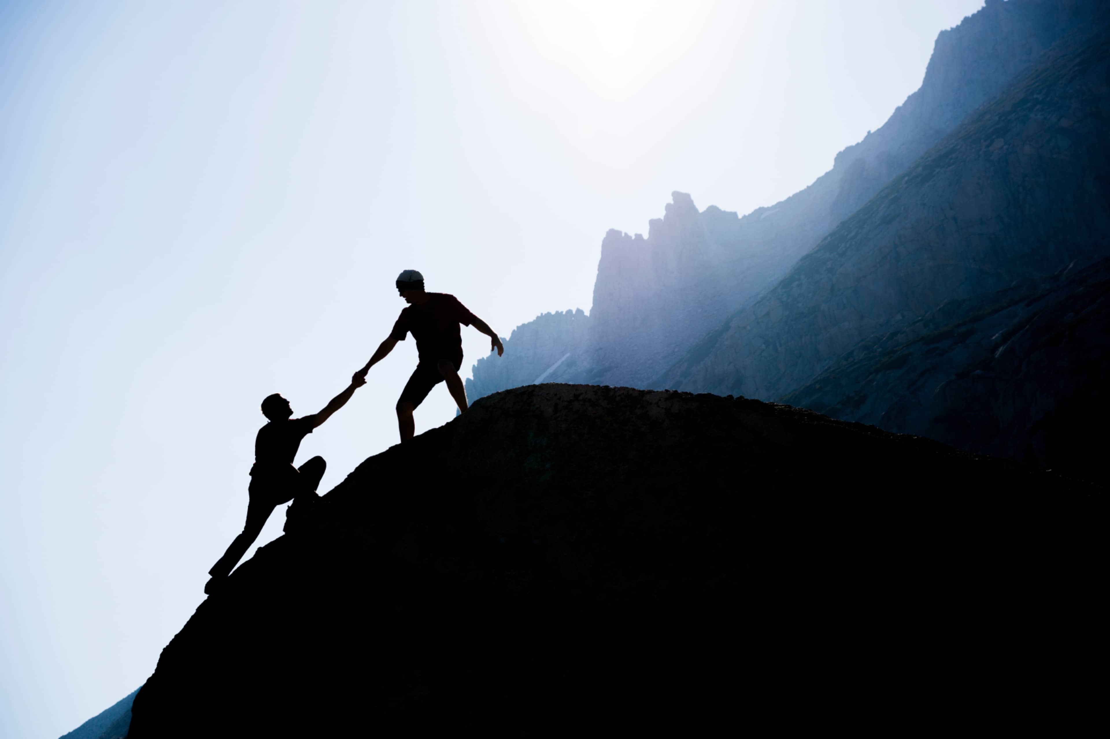 Two people climbing up a mountain