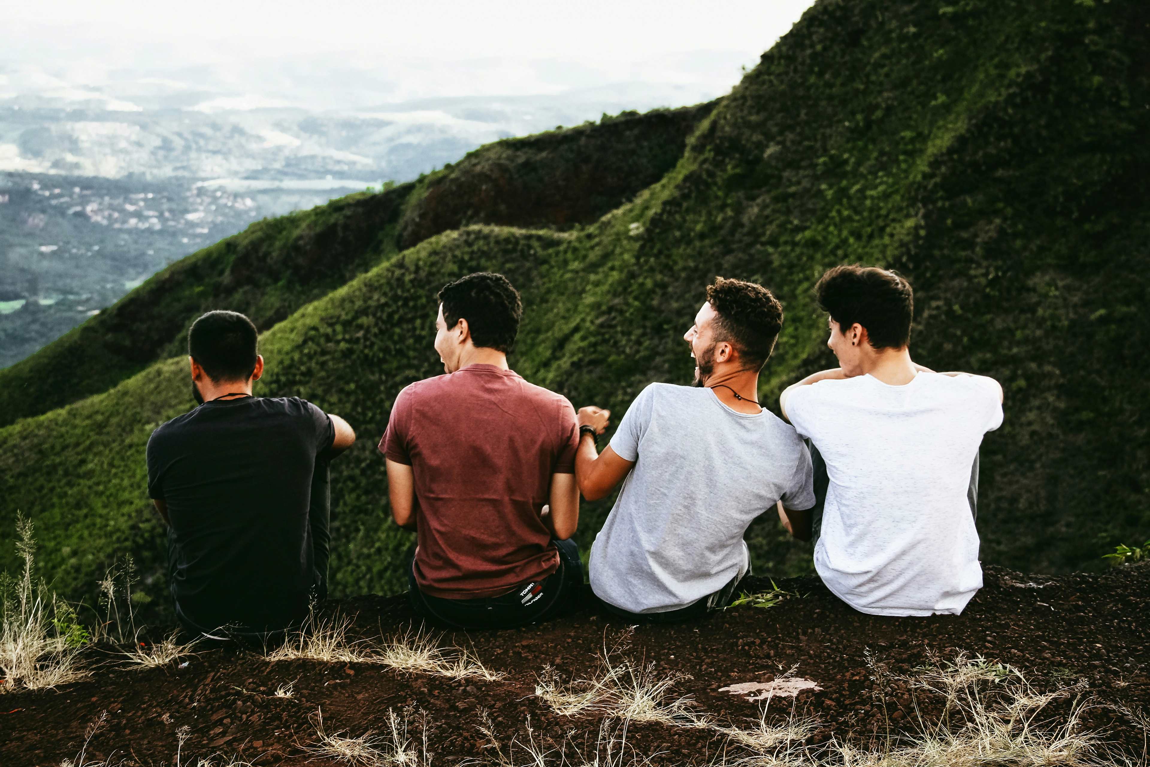 Men sitting on a ledge in the mountains