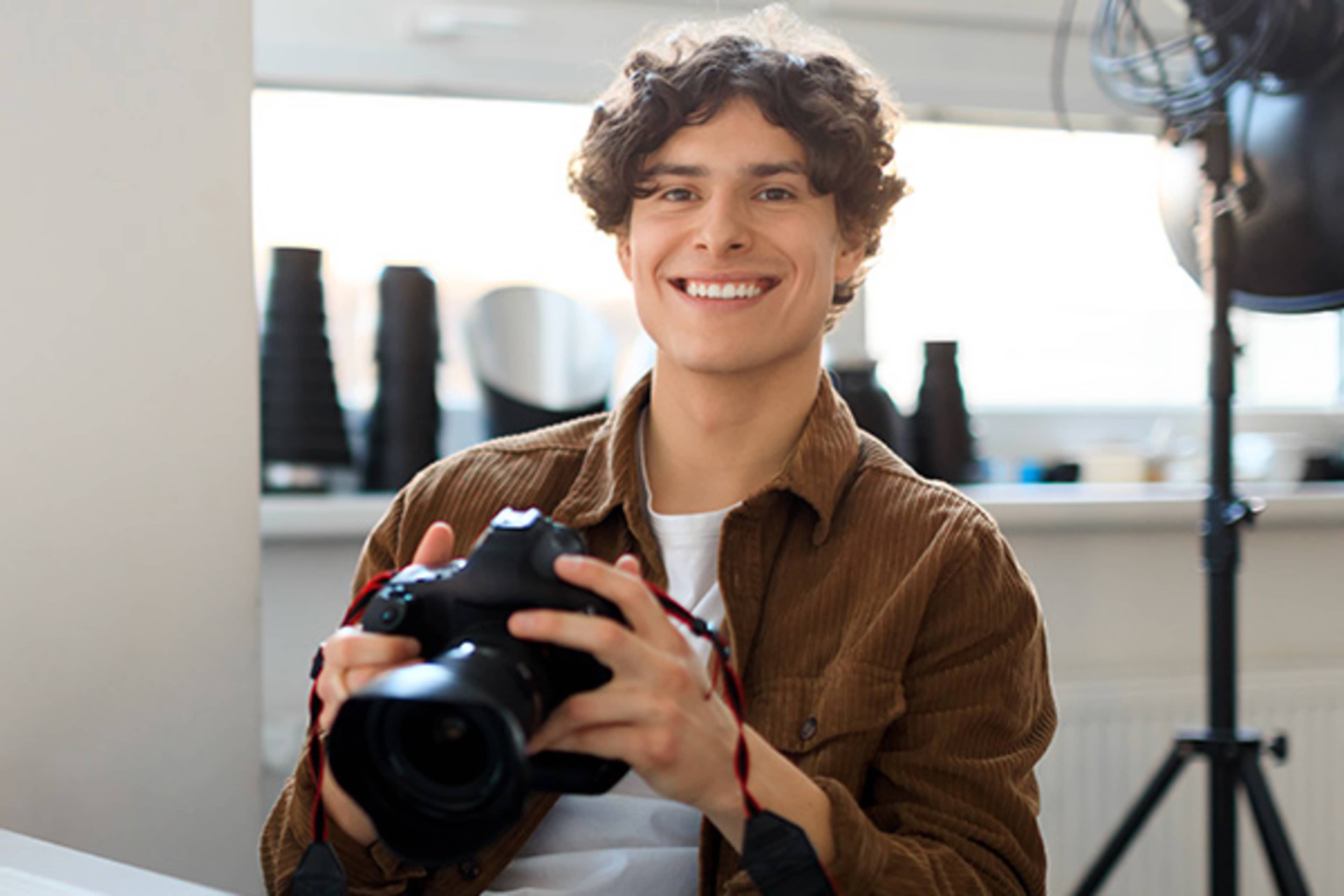 Young man smiling while holding a camera
