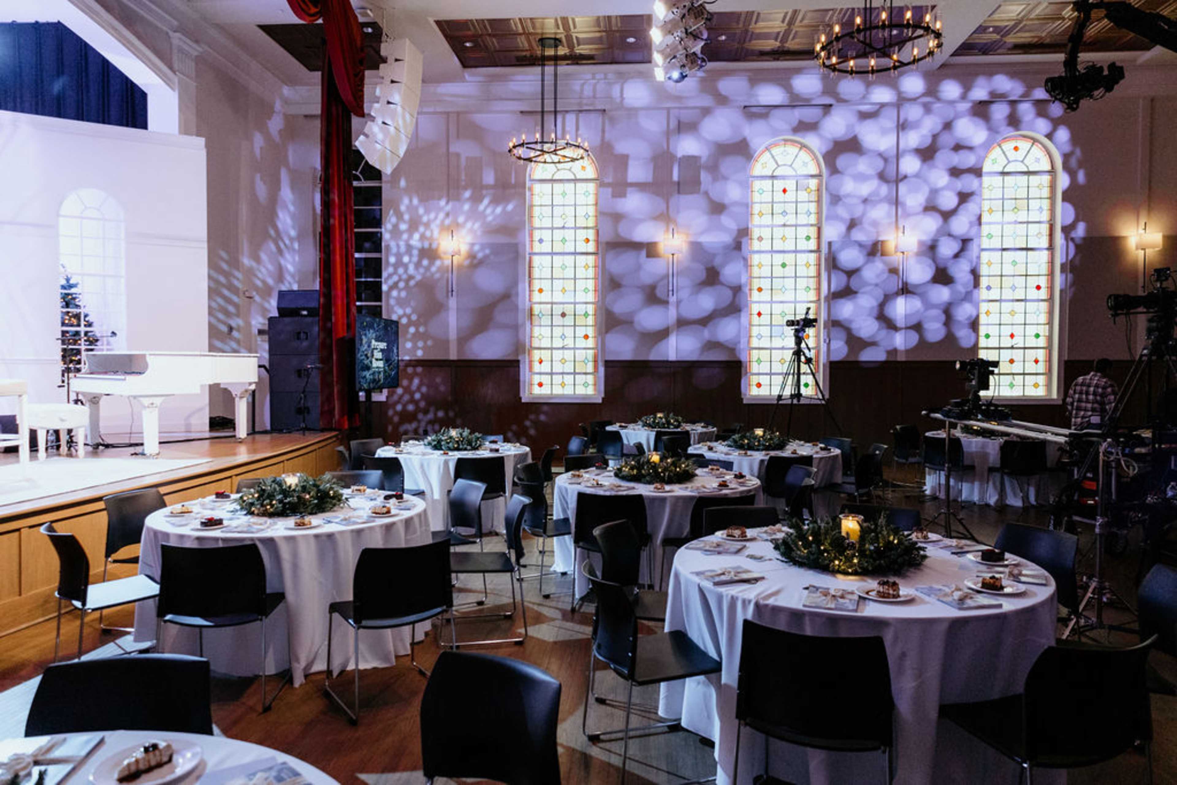 Tables with Christmas centerpiece and candles next to stage