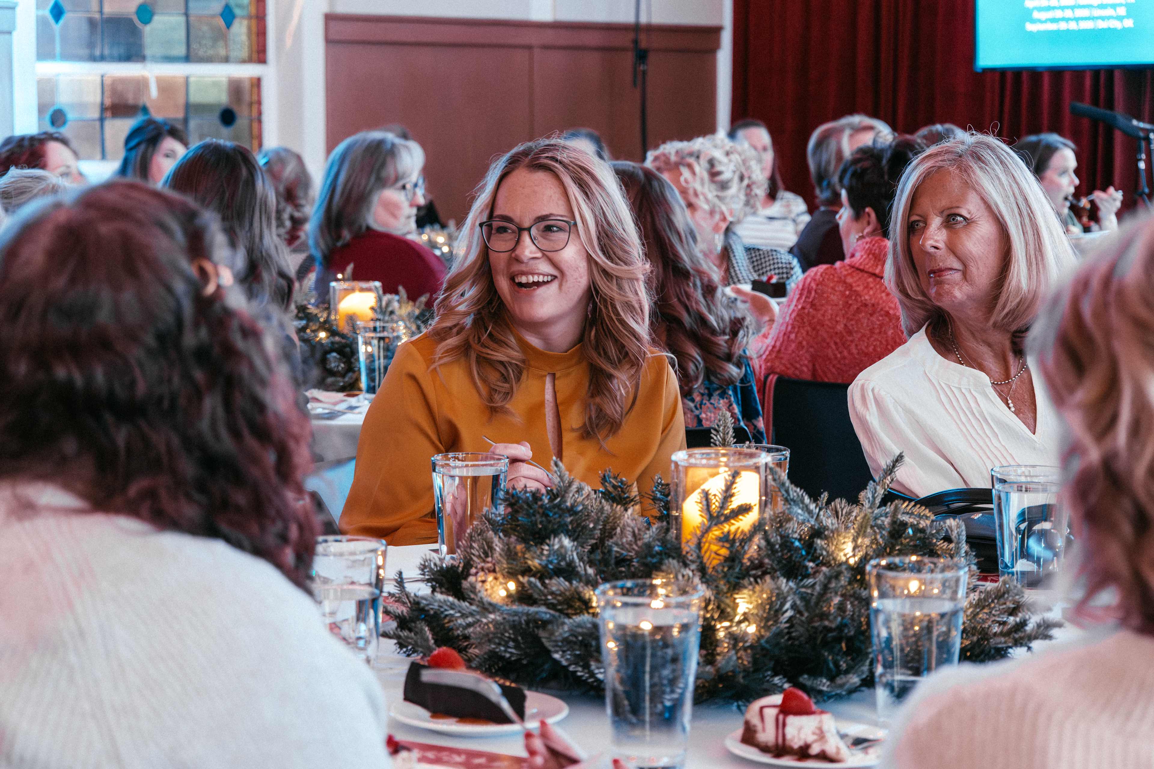 Women sitting around table with candles, talking and laughing