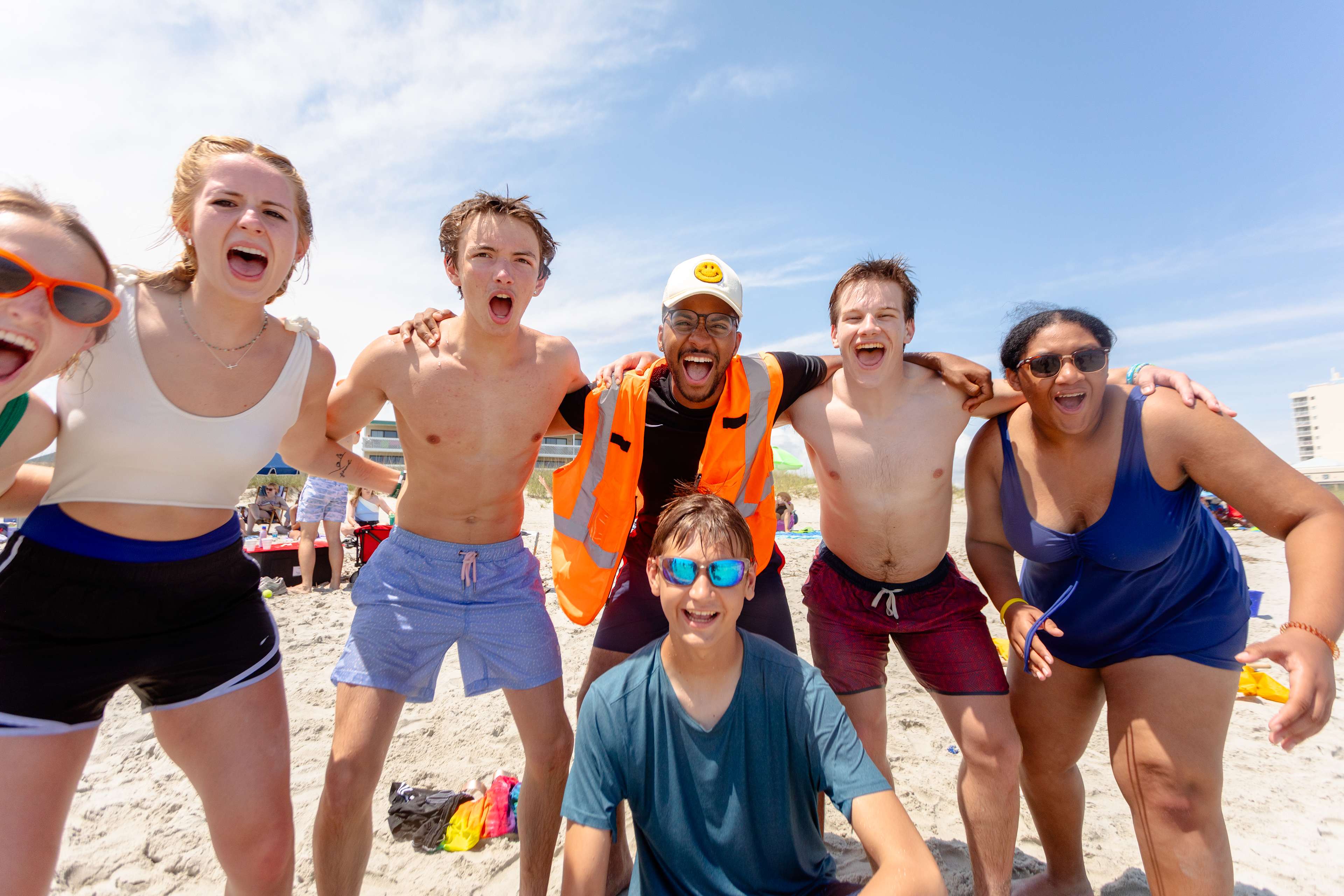 six teenagers on beach with arms around each other