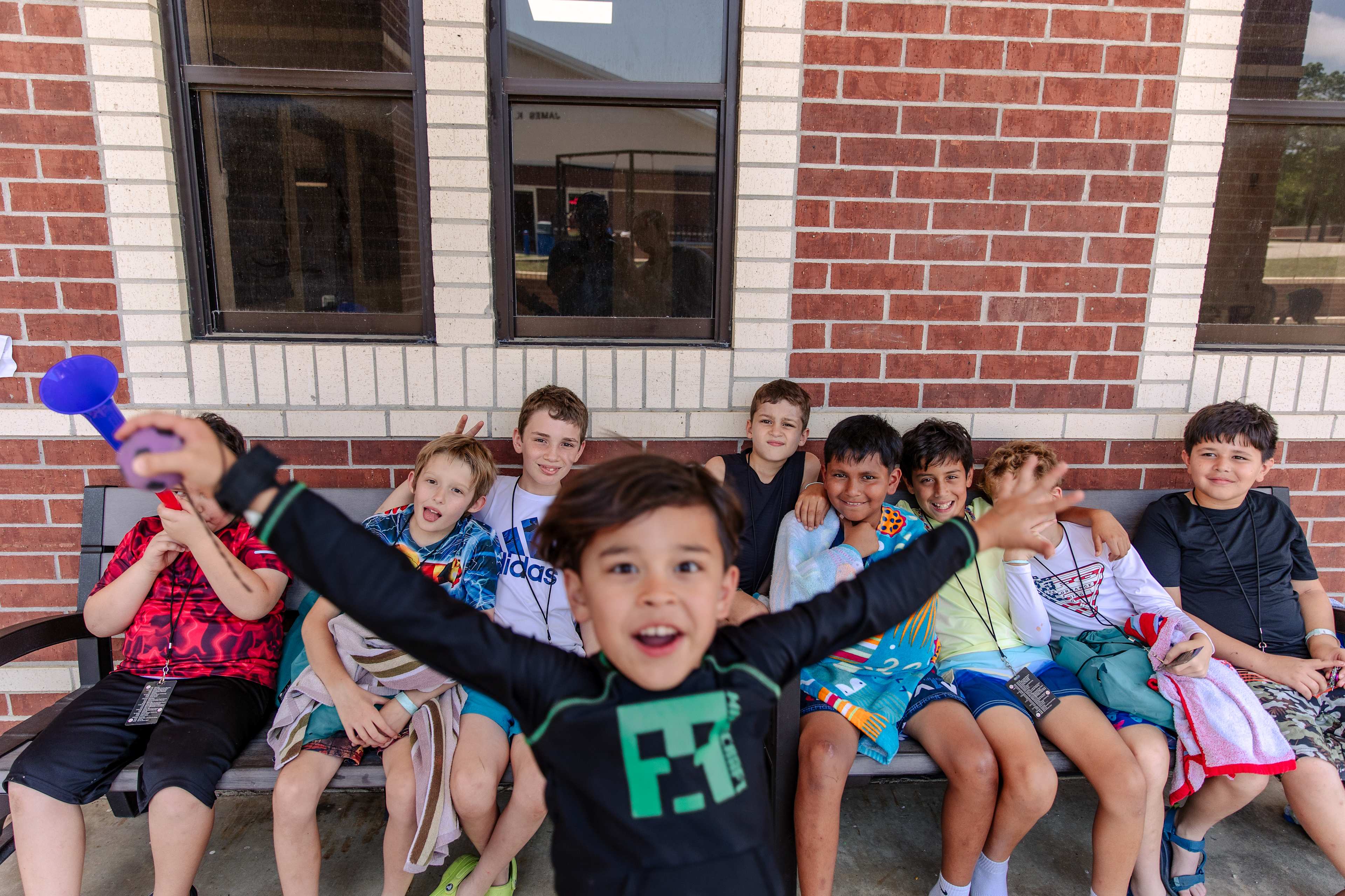 kids on bench with boy in front with arms out wide
