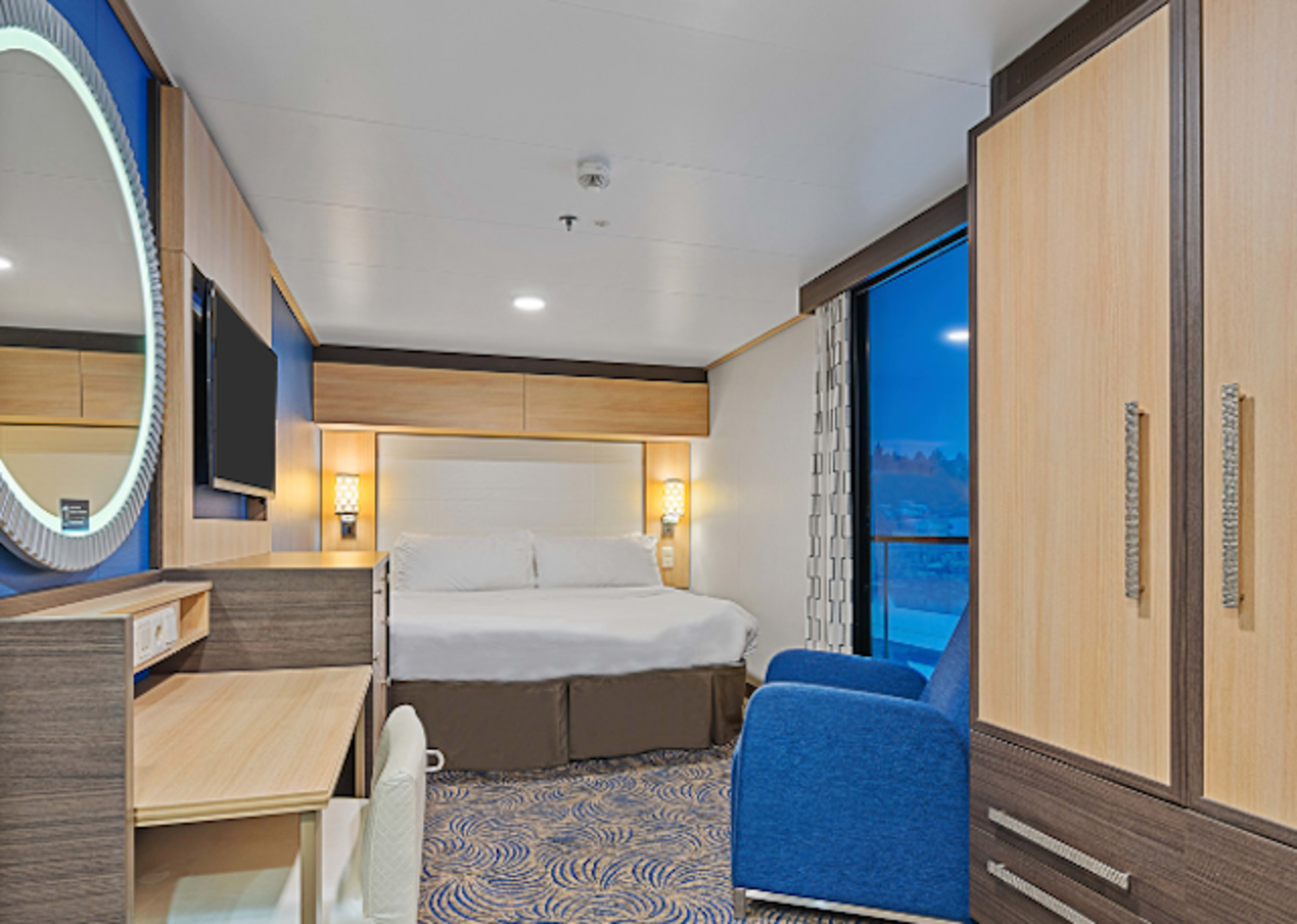 cruise stateroom with bed, desk, and mirror