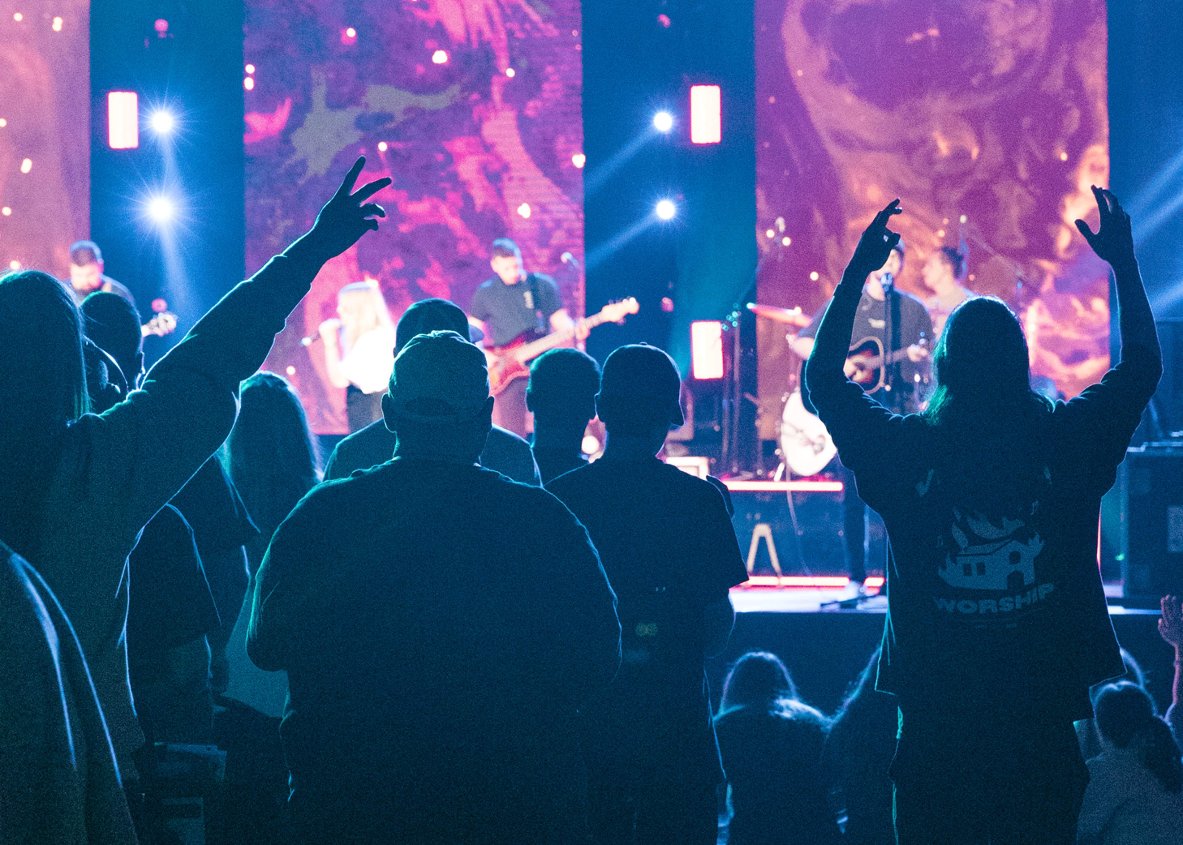 Audience worshipping with raised hands during a live music performance on stage