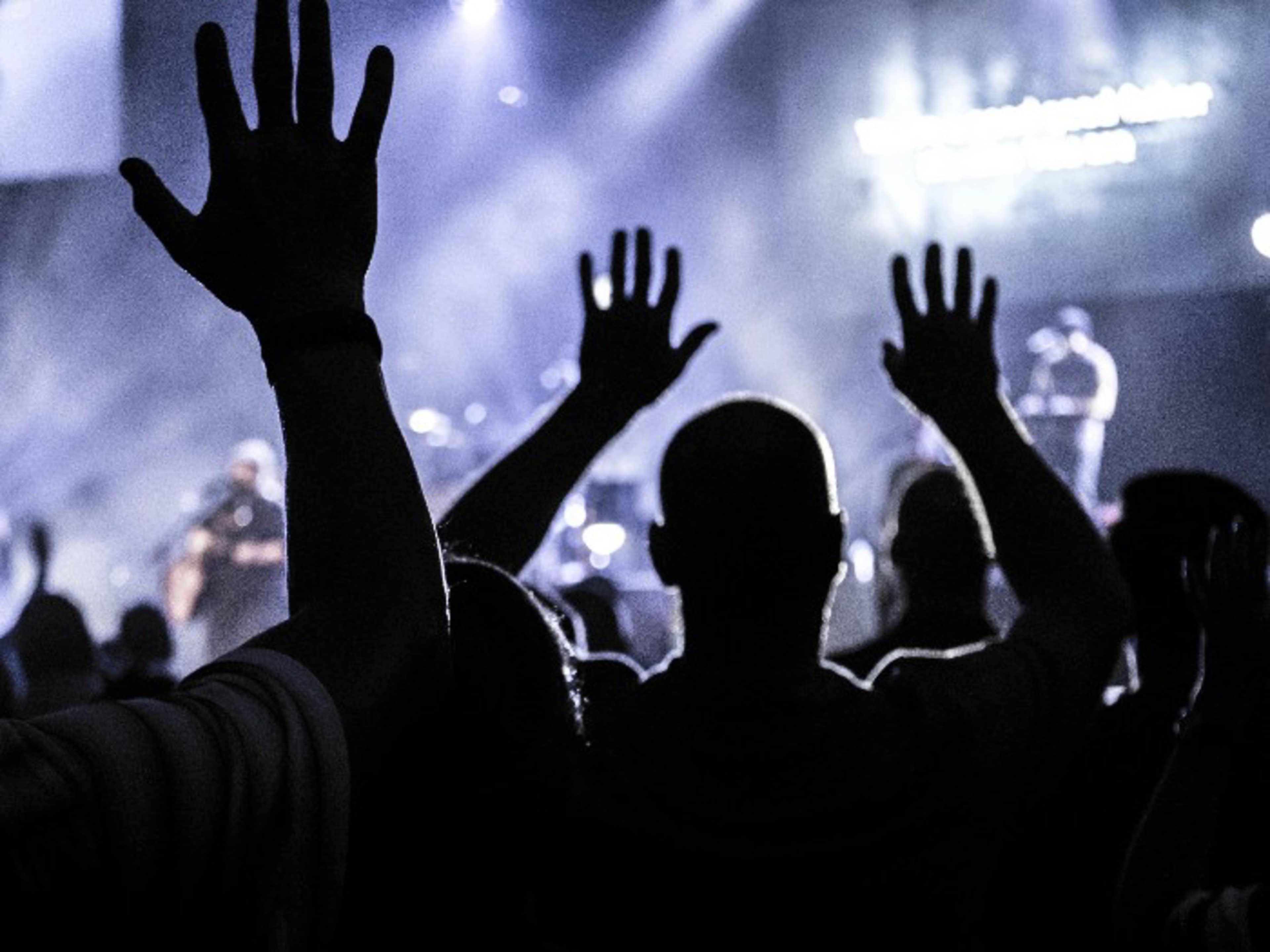 Silhouettes of people with raised hands during a worship service
