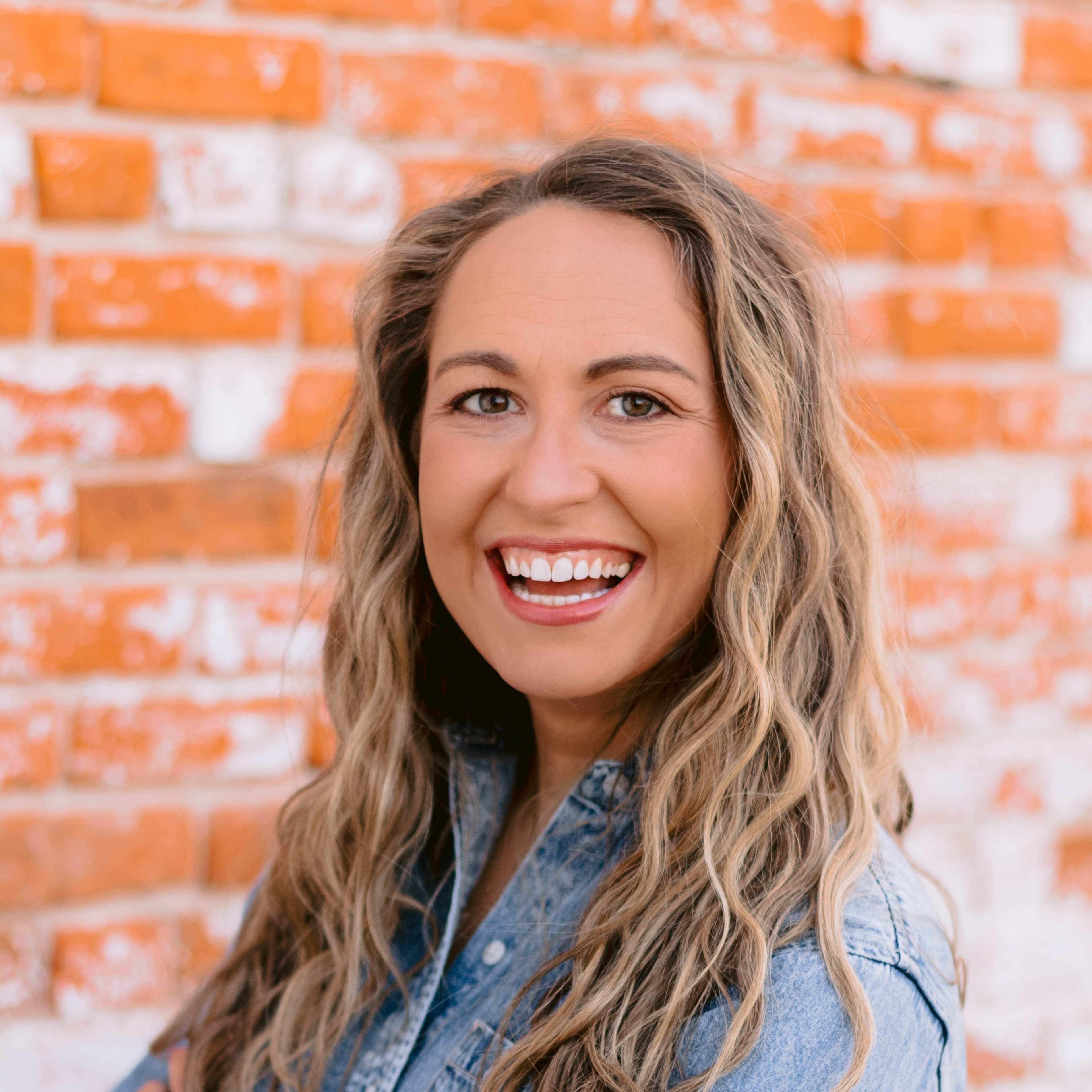 Kate Downing smiling in front of brick wall