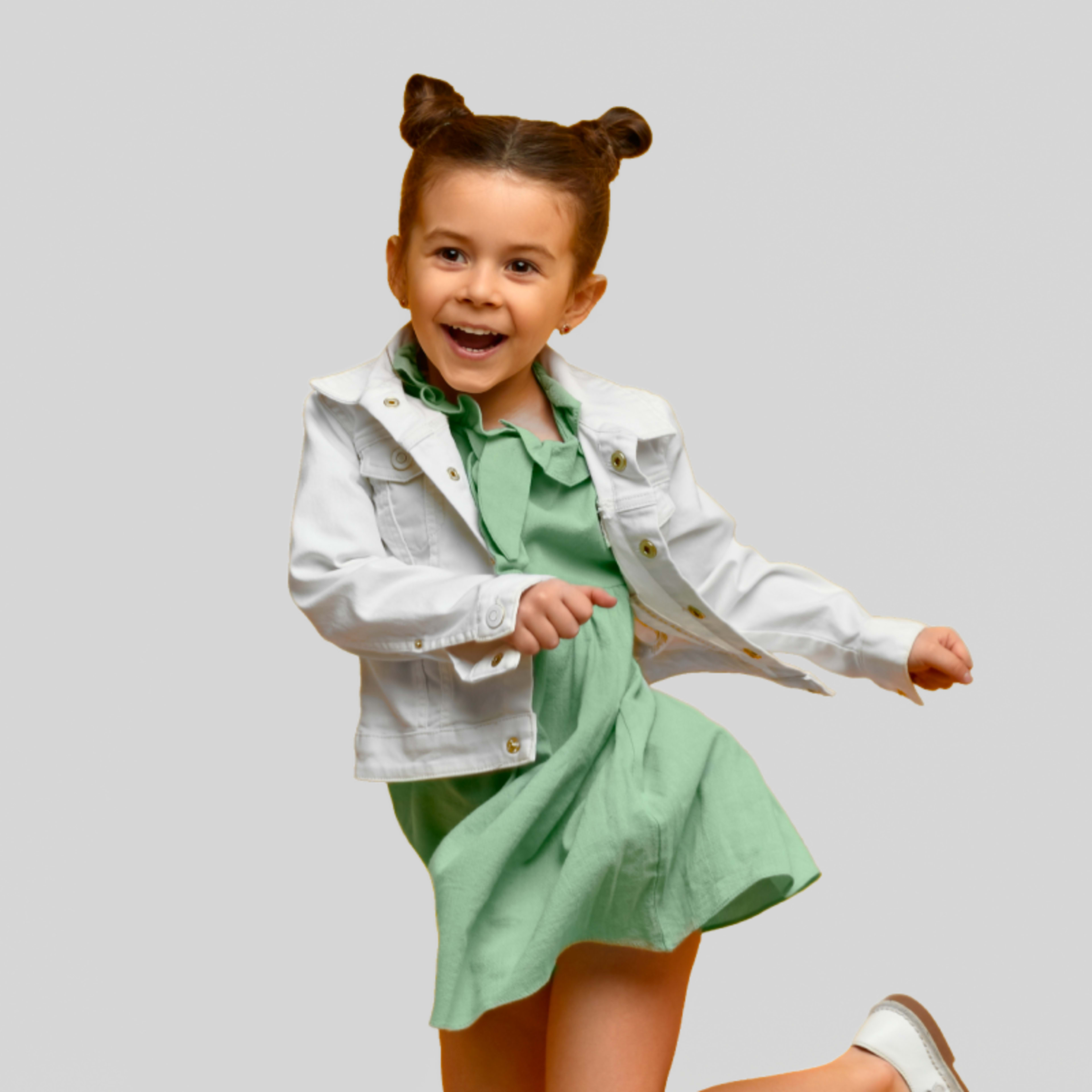 girl in jean jacket and dress jumping
