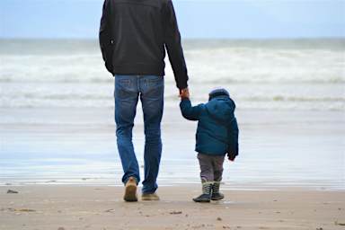 father and son holding hands on the beach
