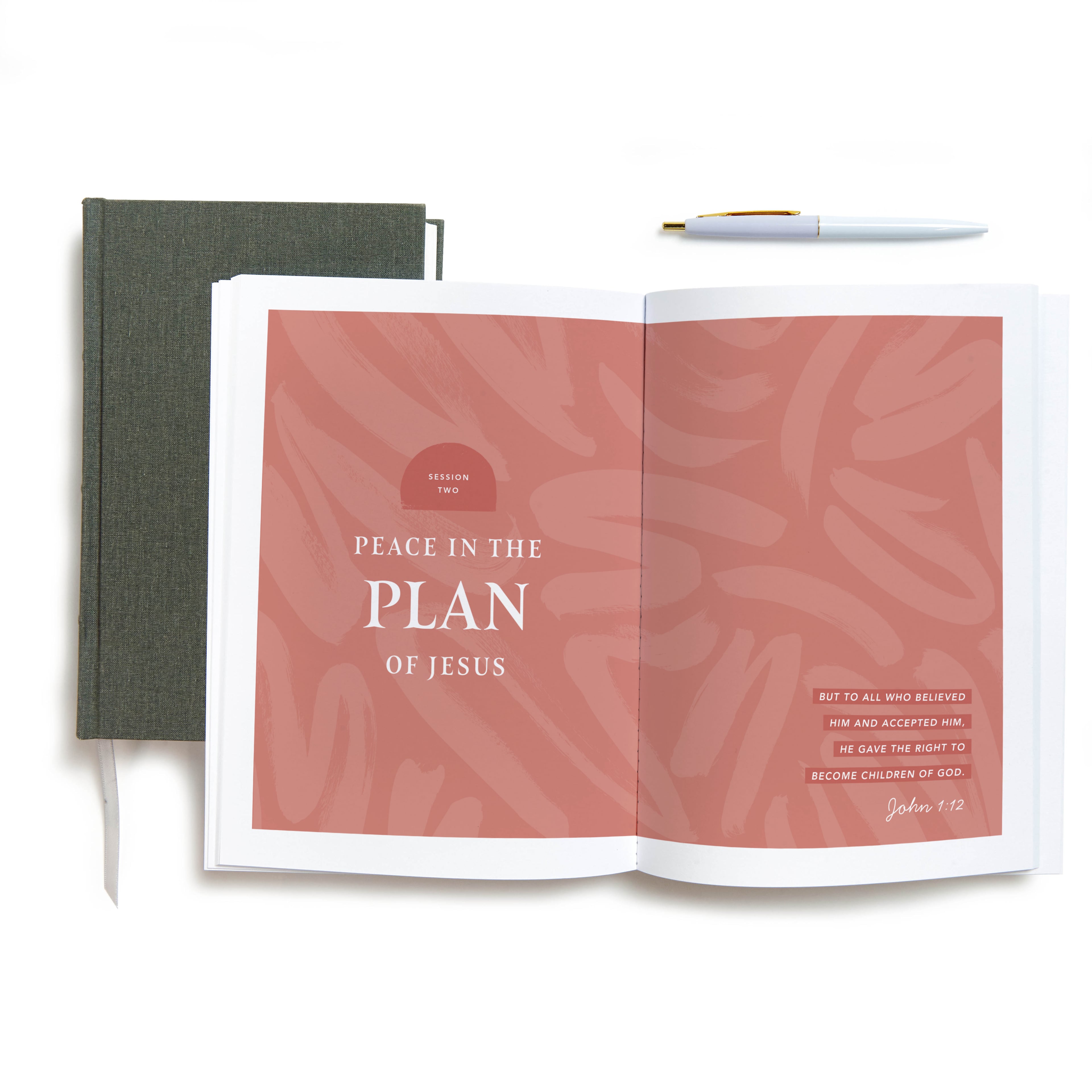 Open book displaying session titled Peace in the Plan of Jesus with a green notebook and pen beside it.