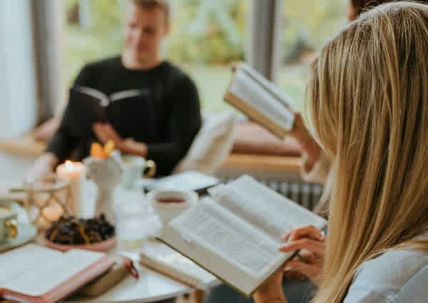 men and women sitting at table reading Bibles