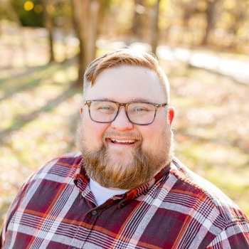 Chad Higgins in flannel shirt standing in woods