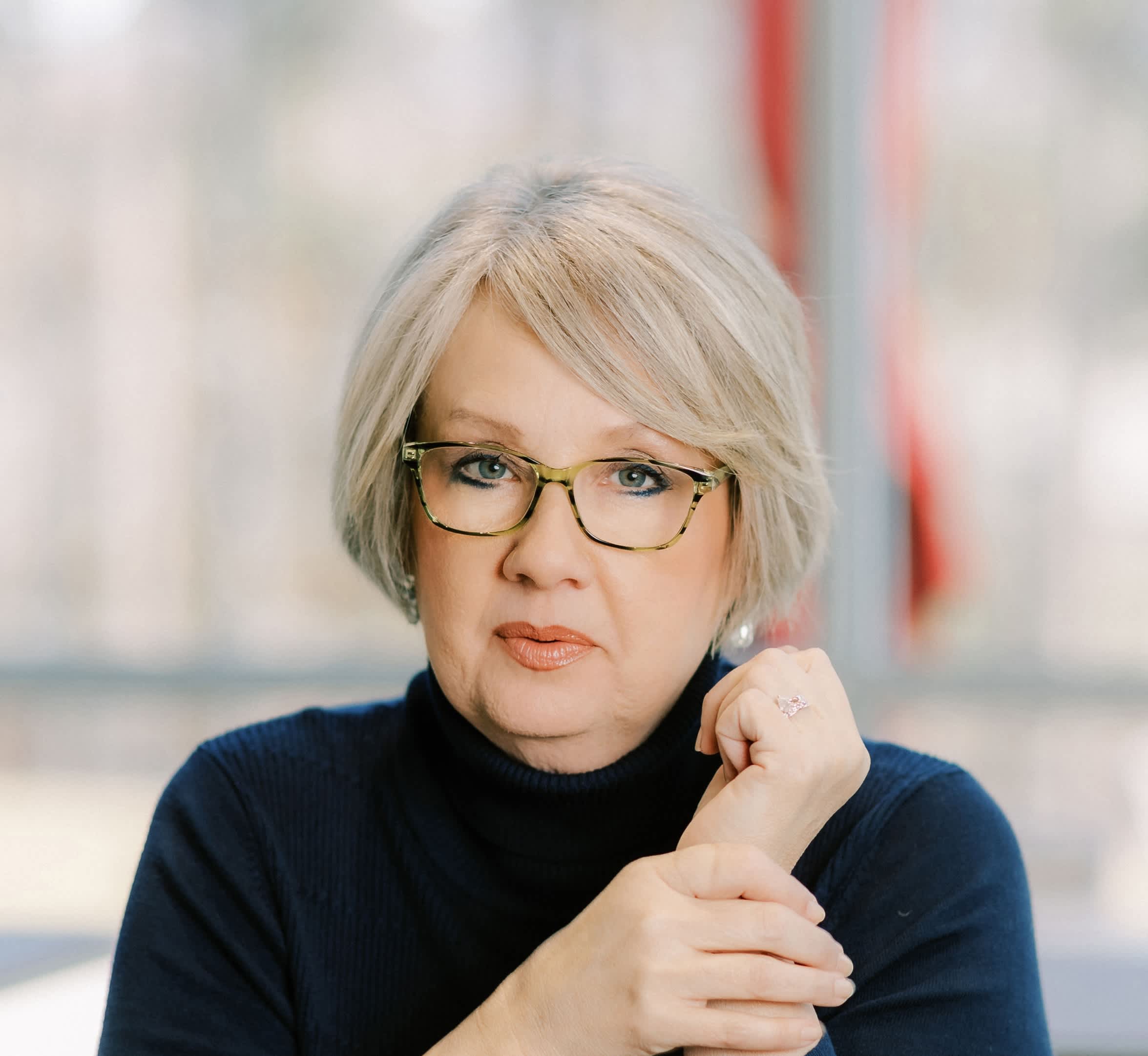 woman with white hair and glasses holding her hand by shoulder