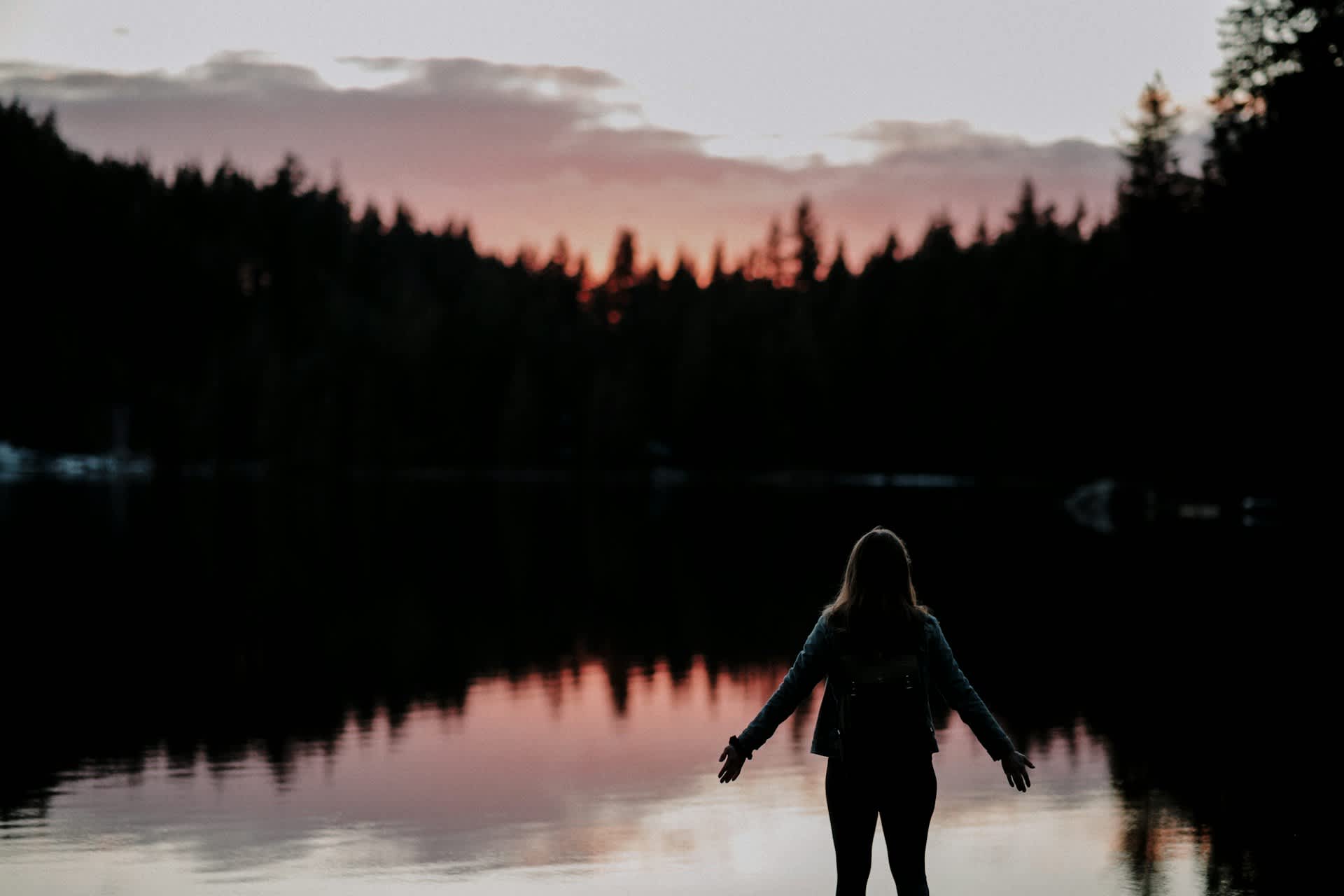 woman with stretched arms in the outdoors at sunset