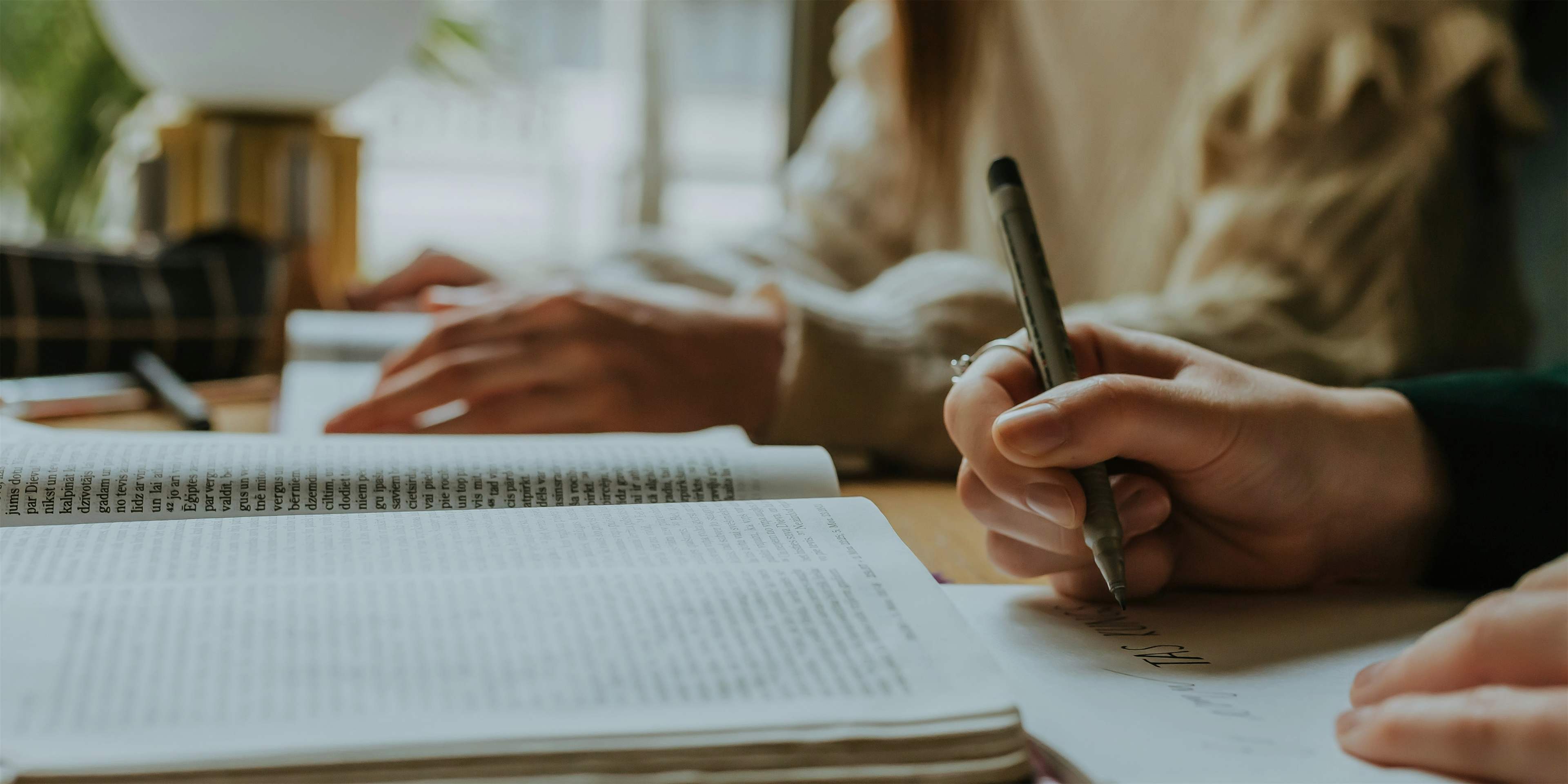 two girls studying at a table with an open notebook on a table