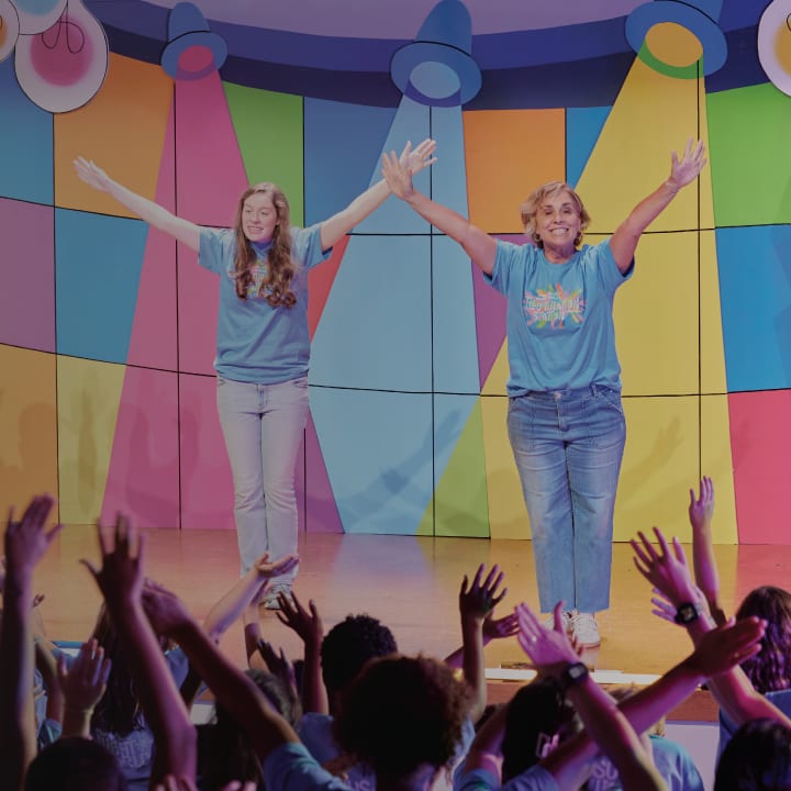Two women leading songs with arms raised