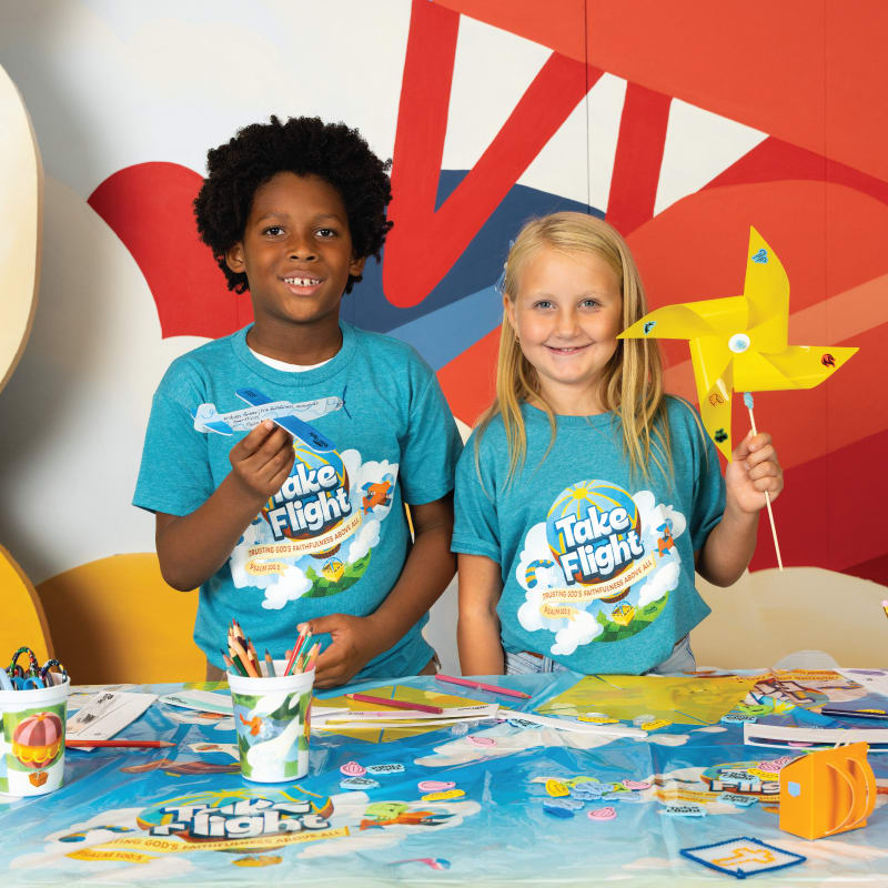 Two kids holding VBS crafts