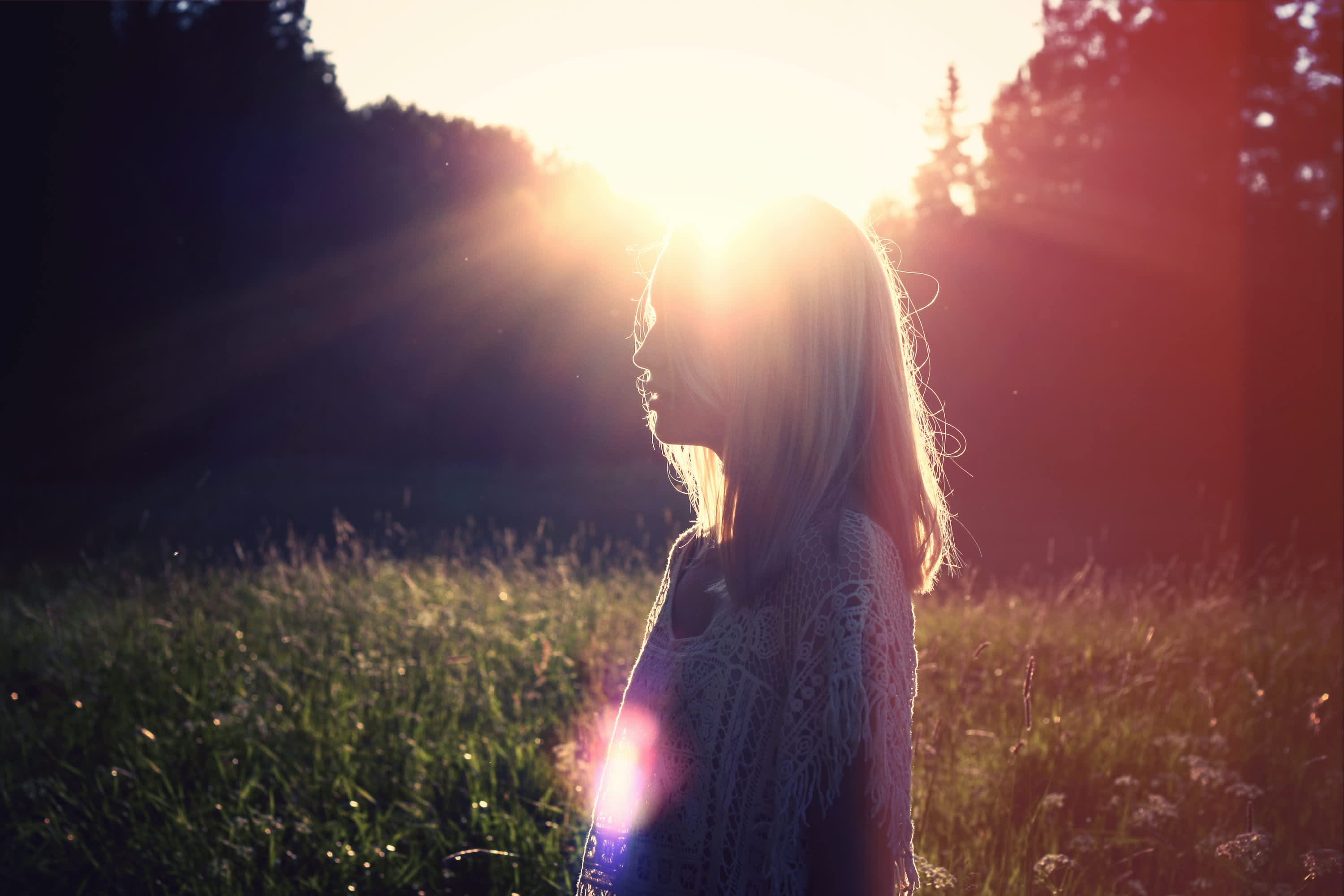 girl in a field with sunlight peeking through