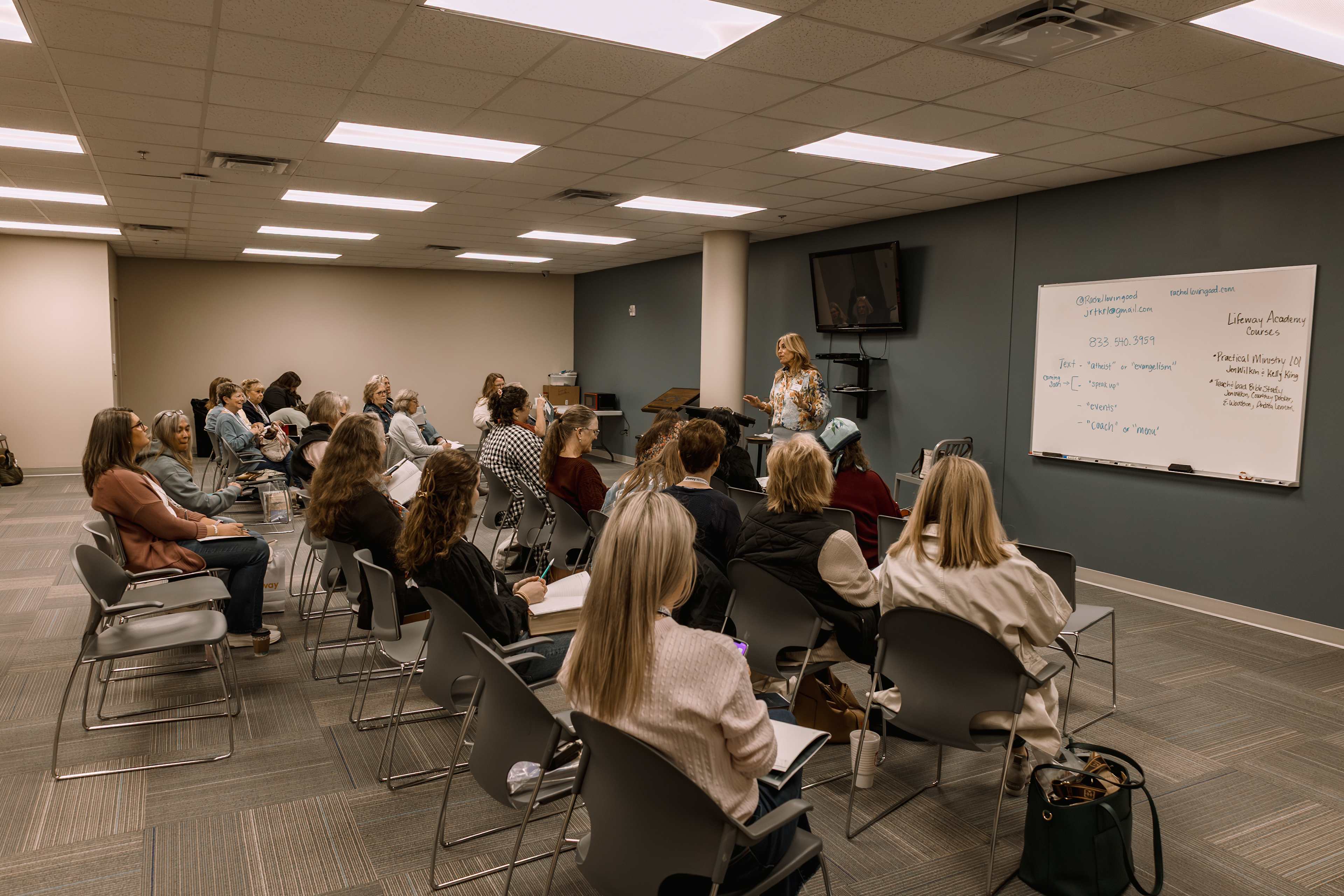 Women sitting in a classroom with teacher and white board in front
