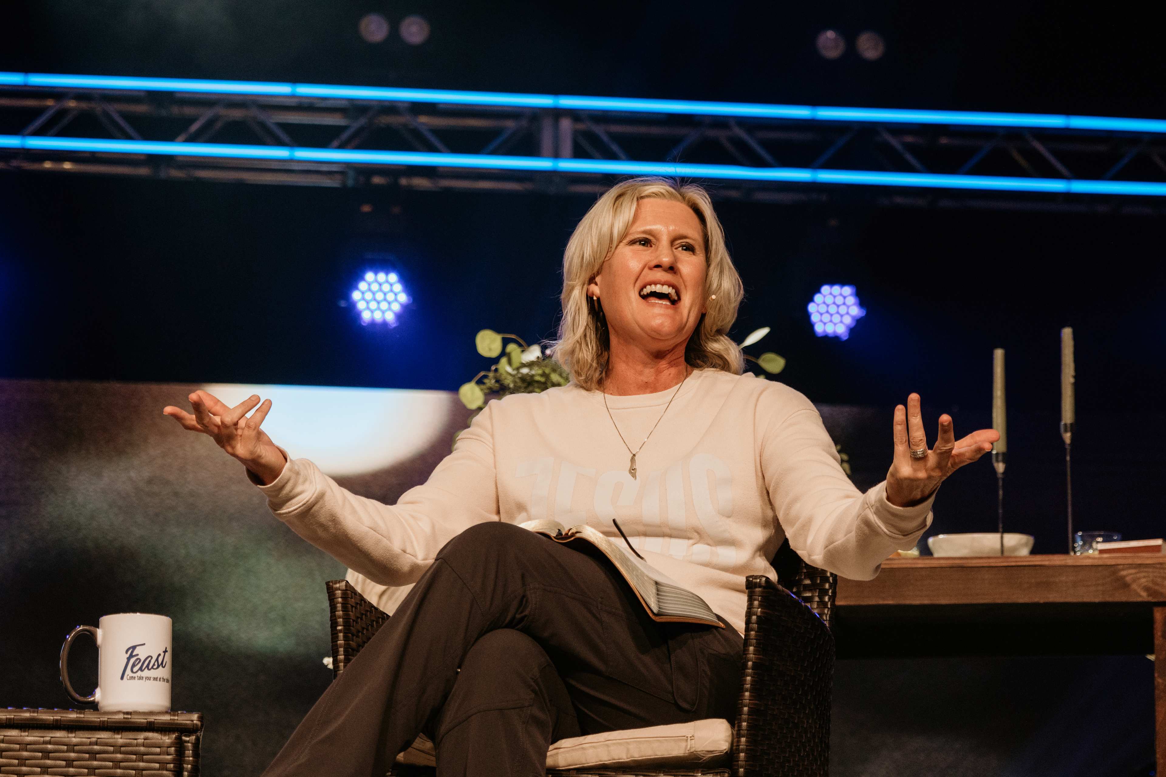 woman in chair speaking with arms raised