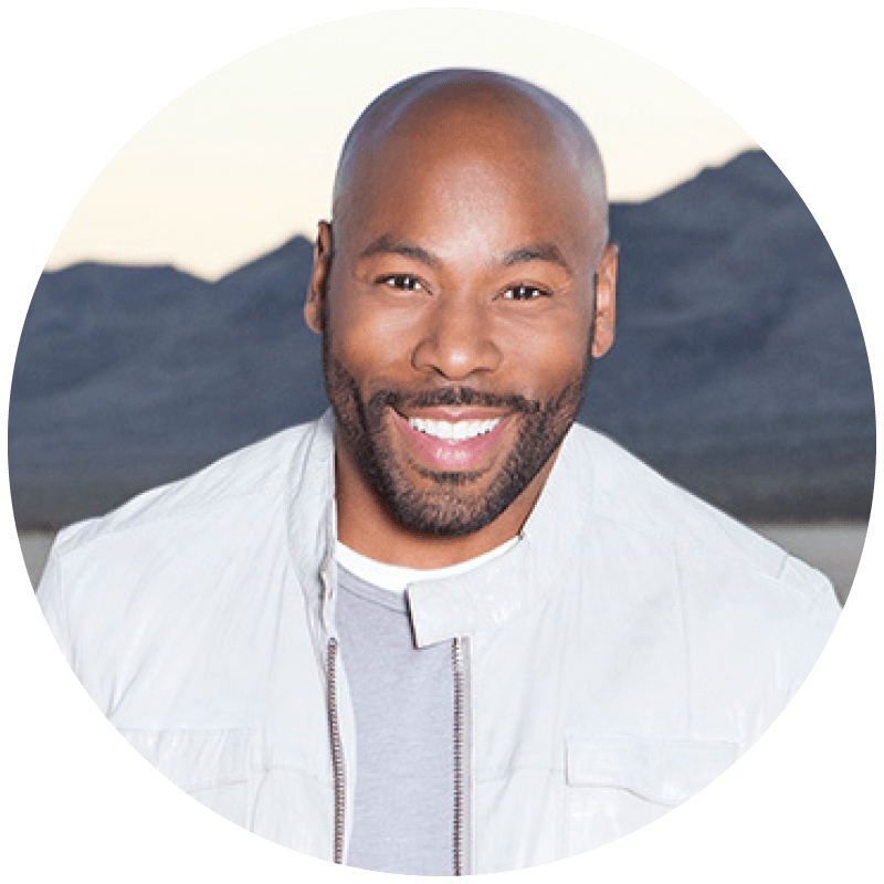 Headshot of a Anthony Evans in a white jacket, set against a mountainous backdrop