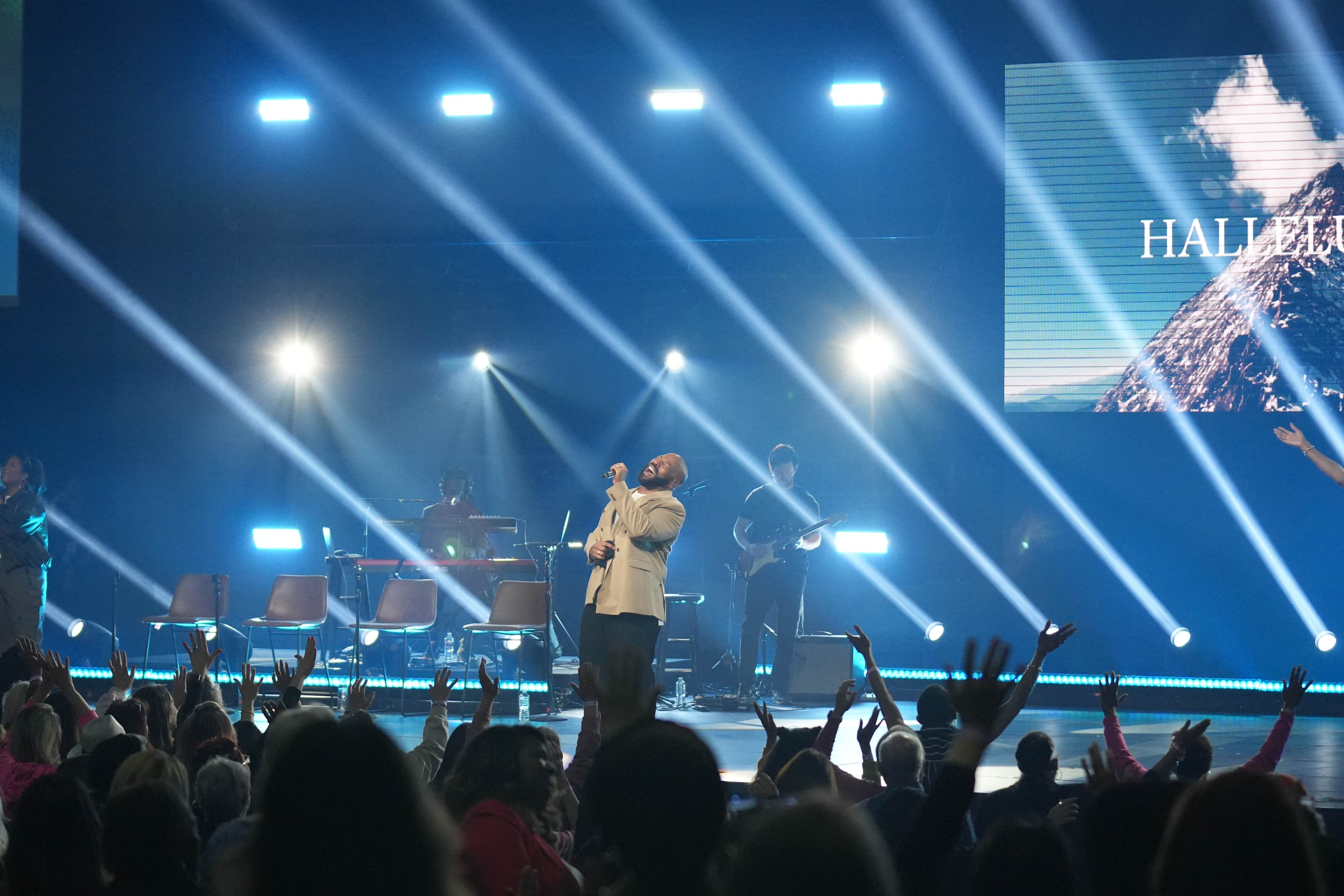 Anthony Evans signing on stage with lights in background