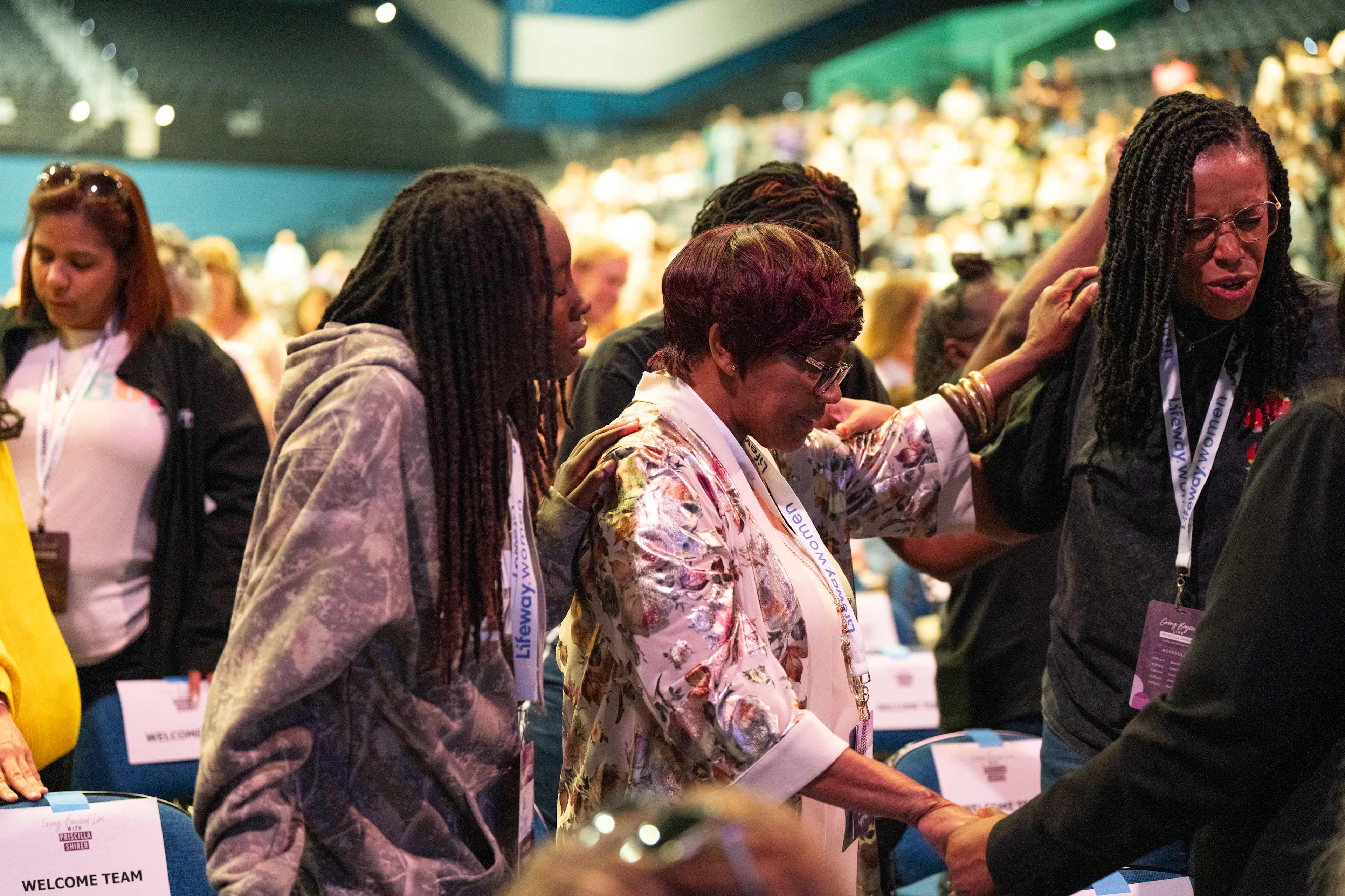 Women standing and praying with hands on each others shoulders