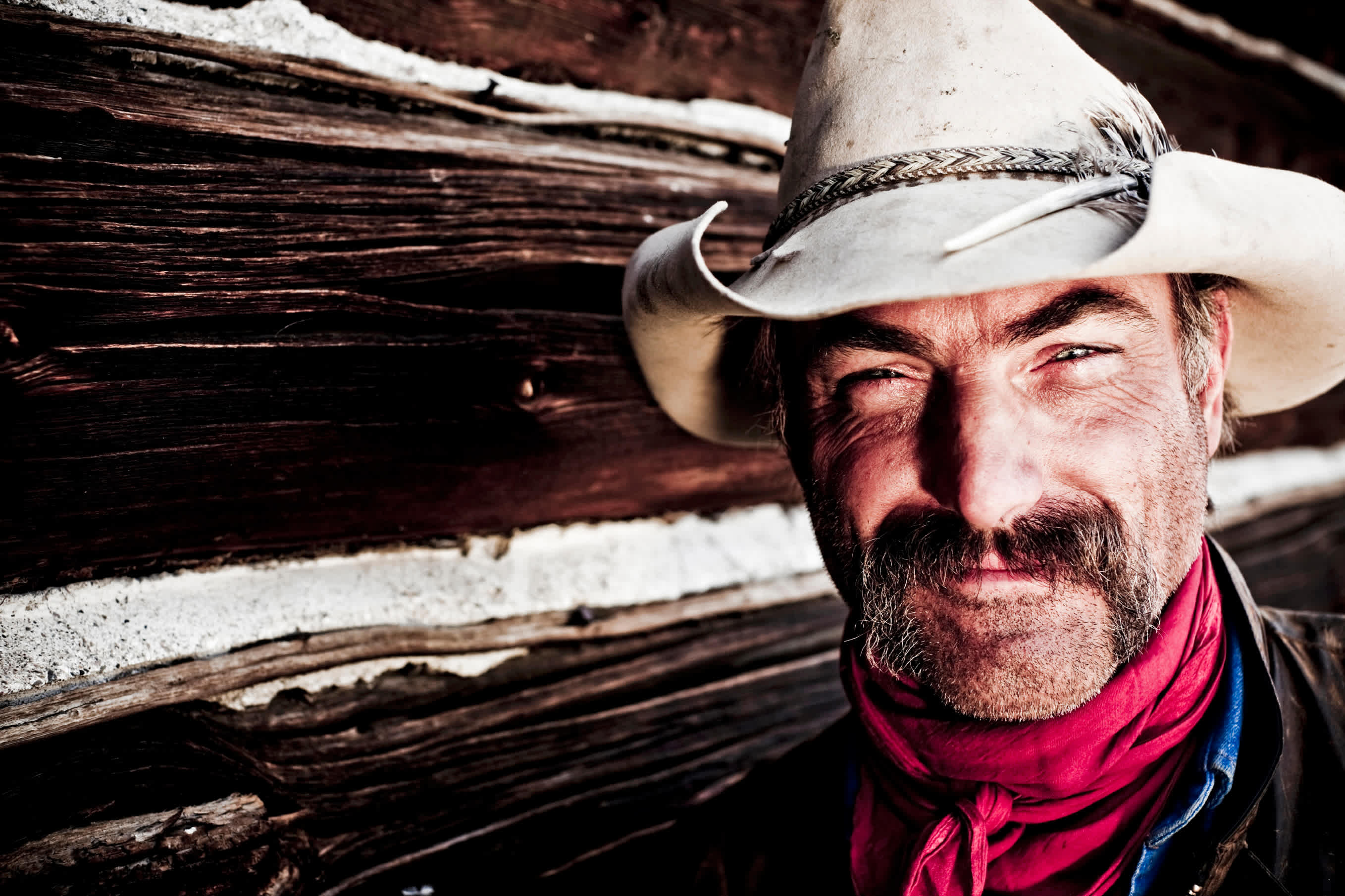 Tough looking cowboy with hat and mustache.