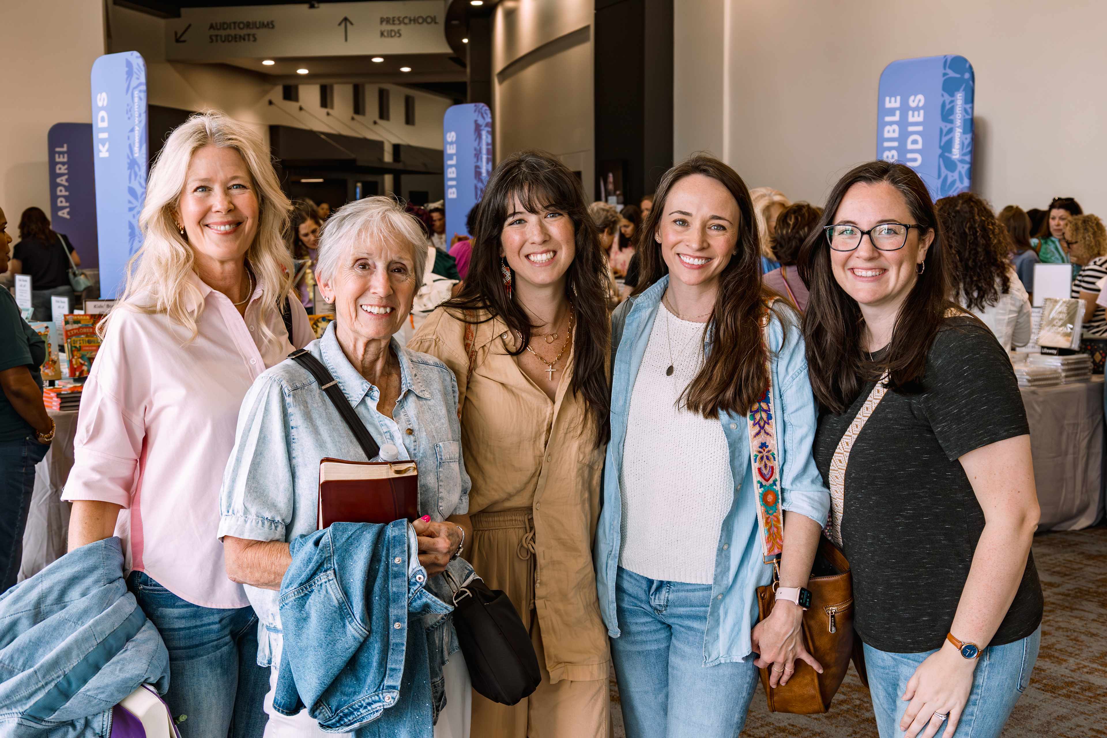 five women in a church lobby smiling and holding books