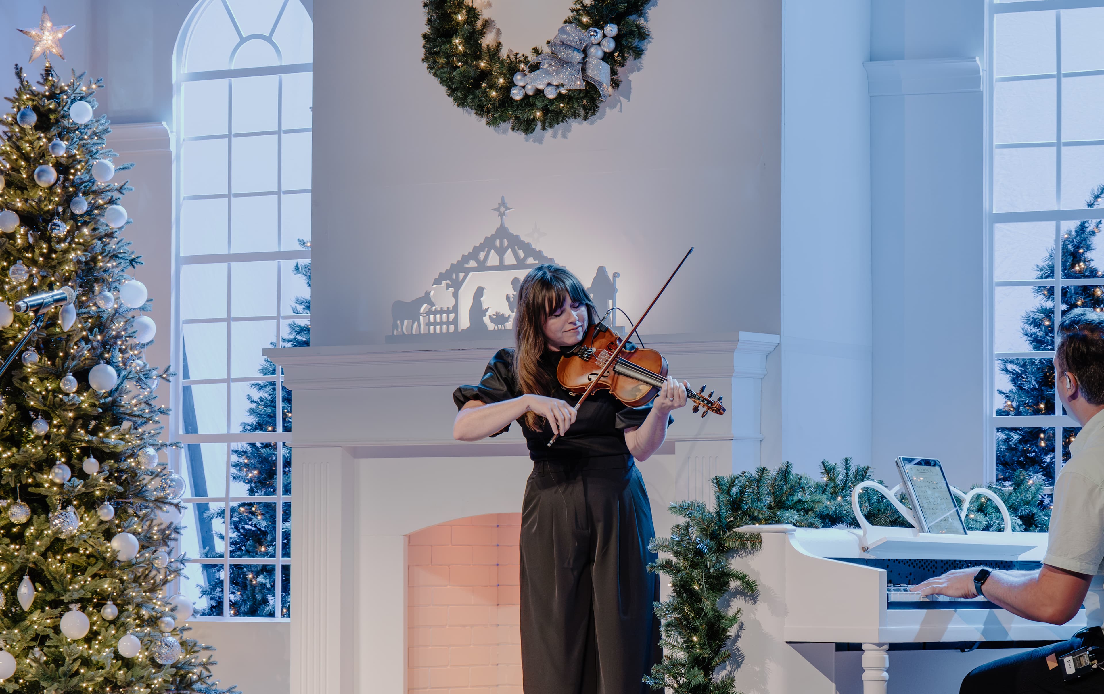 Girl playing violin in front of Christmas tree
