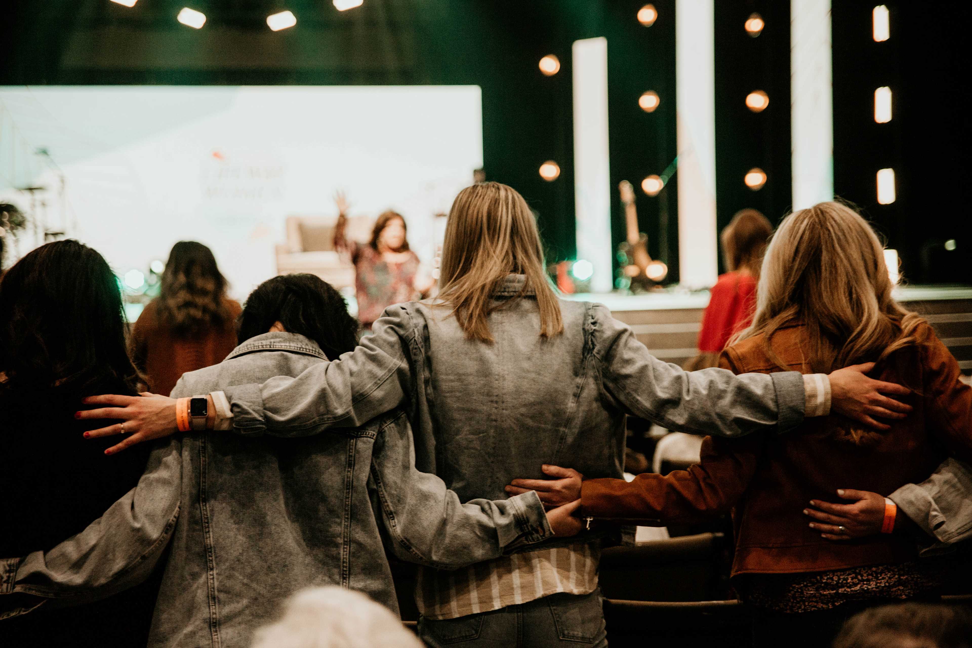 women in worship arms around each other