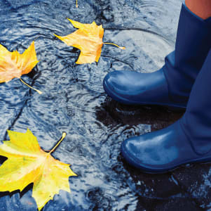 rain boots standing in puddle with leaves